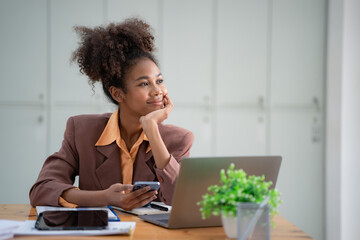 Focused young African female entrepreneur deep in thought while working at a table in a modern...