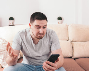 Young man with expression of not understanding something on smartphone.