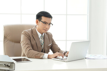 Asian handsome senior successful businessman using computer laptop to researching and working. sit in the private office 