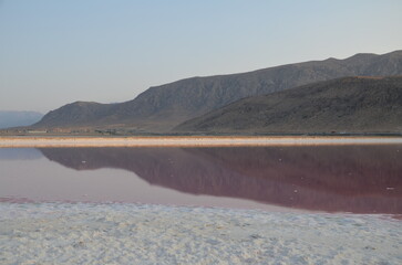 mountain range reflects in the pink coloured water of 