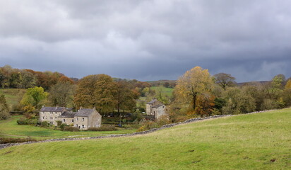 Obraz premium Wharfedale, Yorkshire. Rain Clouds gather over rural hamlet in beautiful countryside.