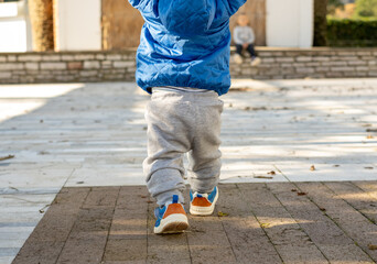 Baby's first steps. Running toddler outdoors. Walking little boy forward to his sister little girl
