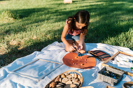 Concentrated child arranging gemstones on wicker mat