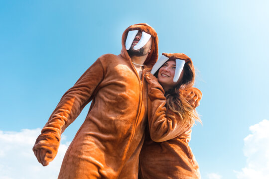 Couple in walrus jumpsuits embracing in from of sky