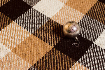 Silver Christmas ball on brown plaid, copy space background.