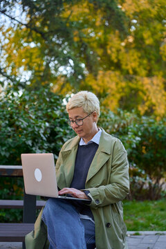 an adult busy woman is sitting in the park with a laptop
