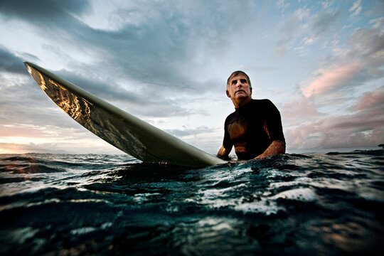 senior surfer sitting on his surfboard
