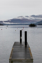 Naklejka premium Jetty on lake Windermere with fog rolling over the mountains