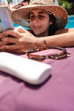 woman using her phone at a swimming pool