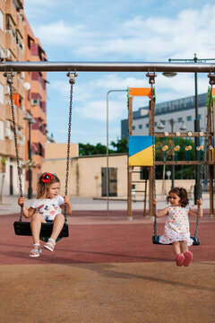 Cute little girls swinging together on playground