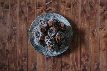 Dried date fruit in a plate. Background wooden floor.