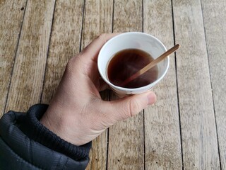 Drinking tea in a cardboard cup.