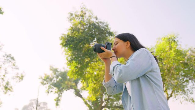 Indian girl clicking photos of nature for her college assignment using a camera