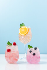 Set of drinks with ice in glasses. Raspberry, blueberry and orange cocktails. Refreshing tropical summer fruit lemonades