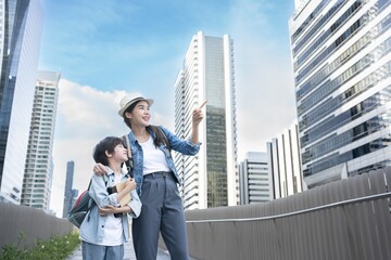 Asian young mother and son looking and pointing in the city. Strong confident woman teaching boy....