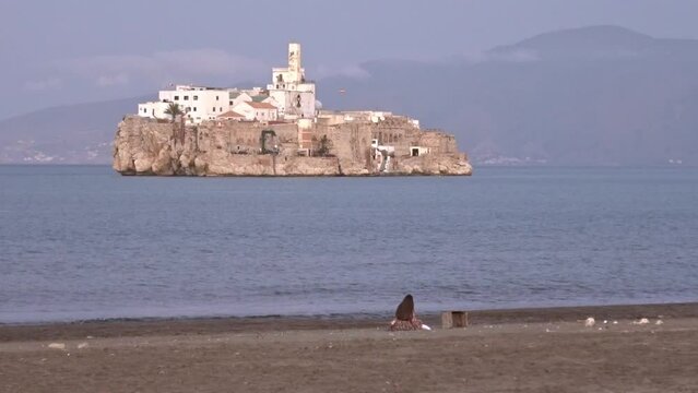 Woman enjoying a warm day in the beach of Al Hoceima, Morocco, with the spanish military island of Alhucemas in front.