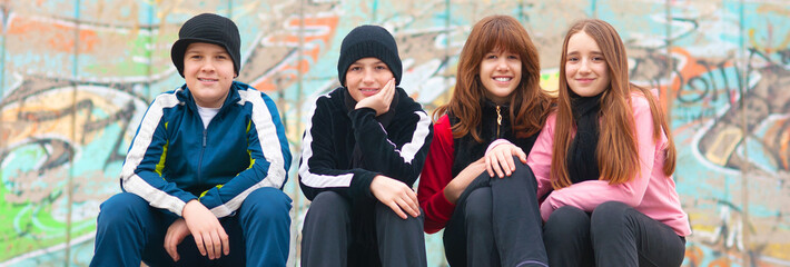 Four smiling teenagers sitting on the stairs in autumn