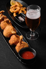 Tempura shrimp, Tempura vegetables and a glass of beer on black background