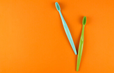 Blue and green toothbrushes on orange background
