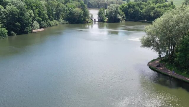 Calm view over natural formed lake surrounded by forest of trees with bridge