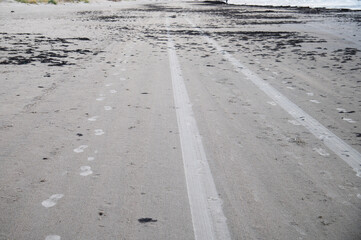 Foot and tire print in sea sand. Unfriendly to nature.
