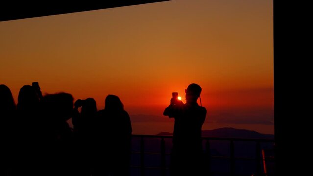 Group of tourists are photographed against the sunset. Vacation in a tropical country. Mystical sunset and human silhouettes
