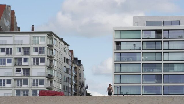 Apartments and flats at the Belgian coast. Young girl walking on the sandy beach. Knokke-Heist, Belgium