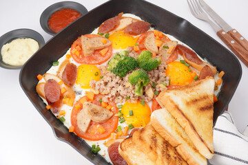Fast food breakfast, fried eggs in pan and vegetables