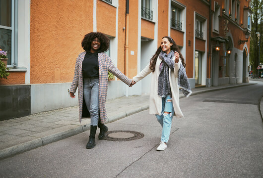 Love, holding hands and lesbian couple walking in street enjoying holiday, vacation and adventure. Fashion, lgbtq relationship and women together for happy interracial marriage, freedom and relaxing