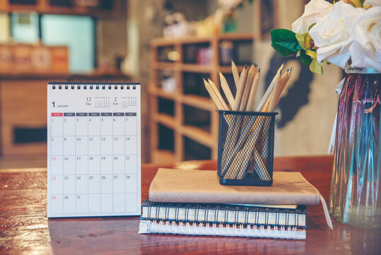 Desk for student education concept. Calendar, Stationery, Book,  and pencil for study for exam placed on wooden School table with library background for student plan to work at home office.