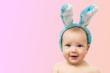 Cute funny baby with bunny ears on a colored background. Easter greeting card. Baby easter bunny