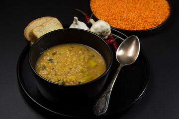 Portion of lentil soup on a black background. traditional cooking
