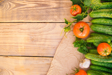 Fresh vegetables on a wooden background. Empty space for the text. Cucumbers, tomatoes, garlic, dill. Top view.