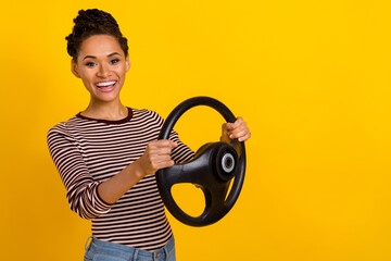 Portrait of pretty cheerful lady arms hold wheel buy new car empty space isolated on yellow color...