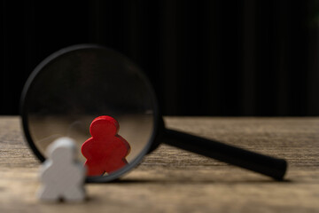 Concept of difference and leadership. White wooden puppets arranged in a circle, but one of them is...