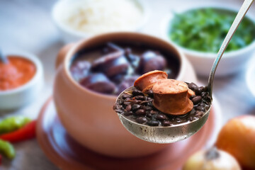 Feijoada. Traditional Brazilian food. ladle with feijoada highlighted and blurred background
