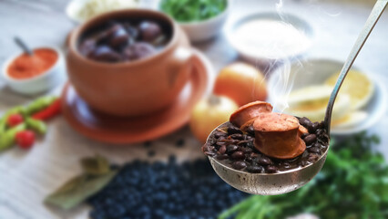 Feijoada. Traditional Brazilian food. ladle with feijoada highlighted and blurred background