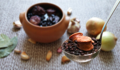 Feijoada. Traditional Brazilian food. ladle with feijoada highlighted and blurred background