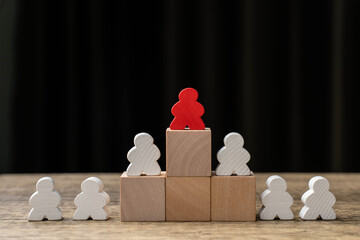 Concept of difference and leadership. White wooden puppets arranged in a circle, but one of them is...