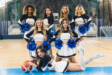 A group of energetic cheerleaders are captured in a dynamic pose on a basketball court. One of them...