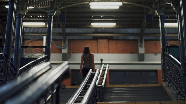 External stairs illuminated by light rays in the evening. Girl leaving the subway station of Etterbeek in Brussels, Belgium.