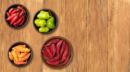 Assorted peppers over wooden table with copy space