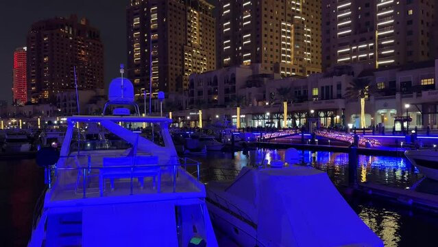 Yacht luxury expensive boat in the club in Doha Qatar Garmin navigation system in the sea water tower hotel buildings in the background at night in pearl lulu mall qanat quartier island katara lusail