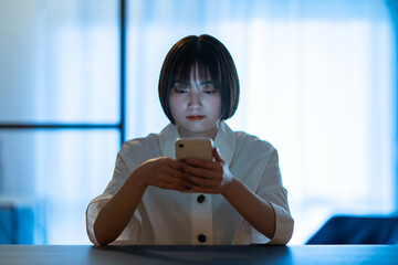 厳しい表情でスマートフォンを見つめる女性