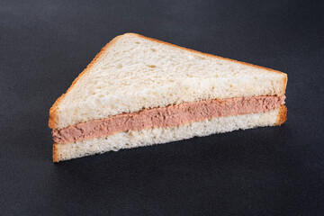 Sandwich with meat pate on a dark background.