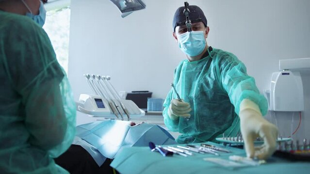 In modern clinic assistants and dentist with special eye in medical mask holds dental instrument that treats teeth. Hydience and healthy