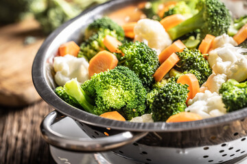 Steamed broccoli, carrots and cauliflower in a stainless steel steamer. Healthy vegetable concept