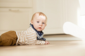 A baby at the age of 8 months learns to crawl at home. Cute little boy crawling on the floor.