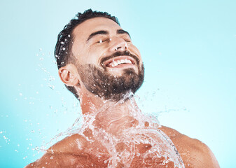 Fototapeta na wymiar Water, splash and skincare with face of man for shower, self care and natural cosmetics. Luxury, hydration and refreshing with model for dermatology, wellness and cleaning in blue background studio