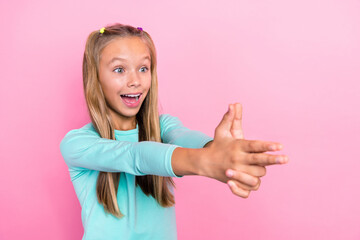 Photo of youngster preteen schoolkid girl open mouth reaction fingers pistol weapon excited positive mood shooting isolated on pink color background